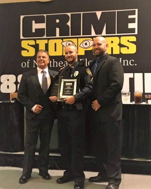 3 police officers in front of the crime stoppers banner
